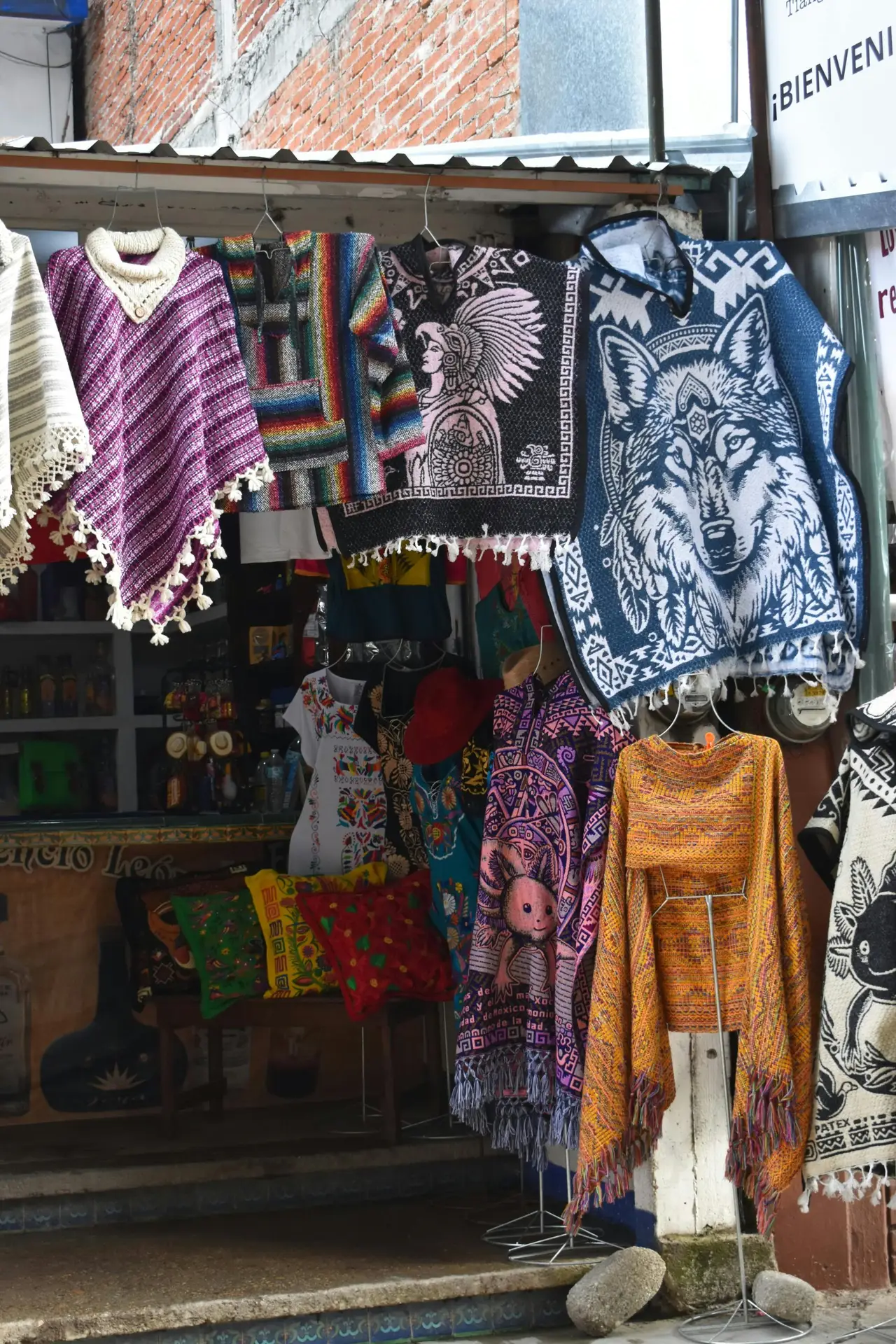 Vibrant handmade ponchos and textiles hung outside a local market shop inviting exploration.
